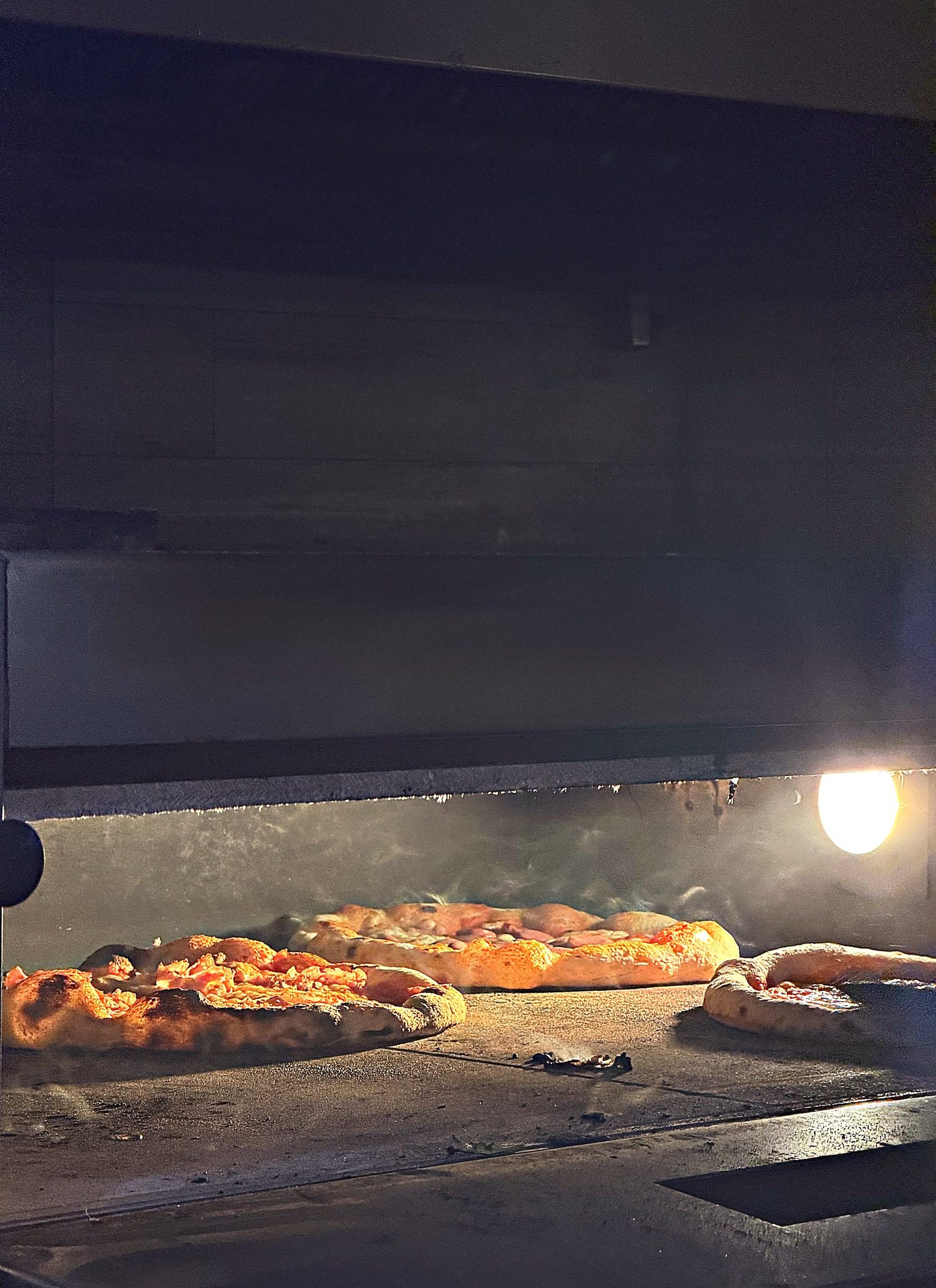 Pizze in cottura nel forno dell'Angolo Rosso