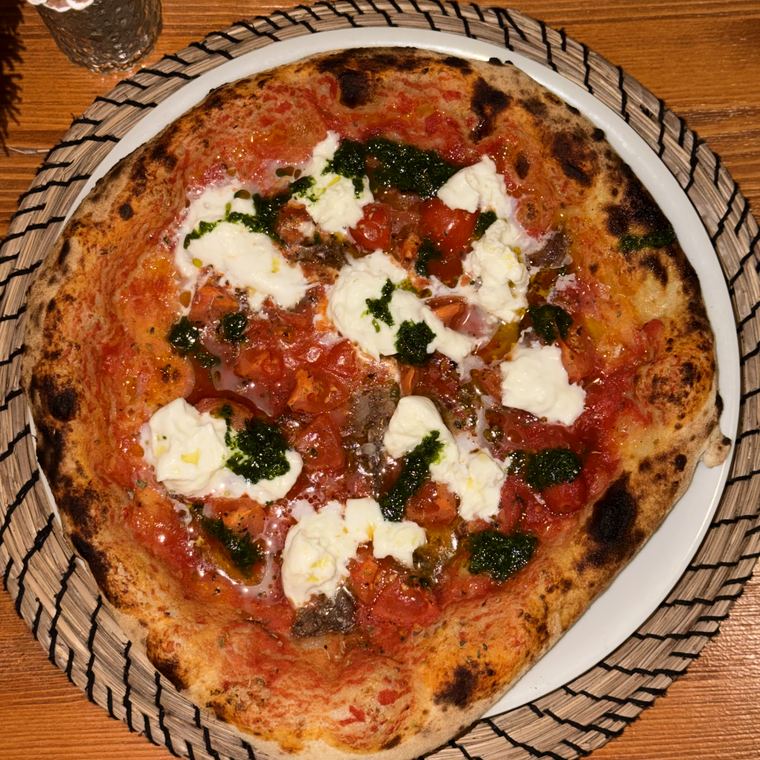 Pizza con pomodoro, burrata e salsa verde vista dall'alto