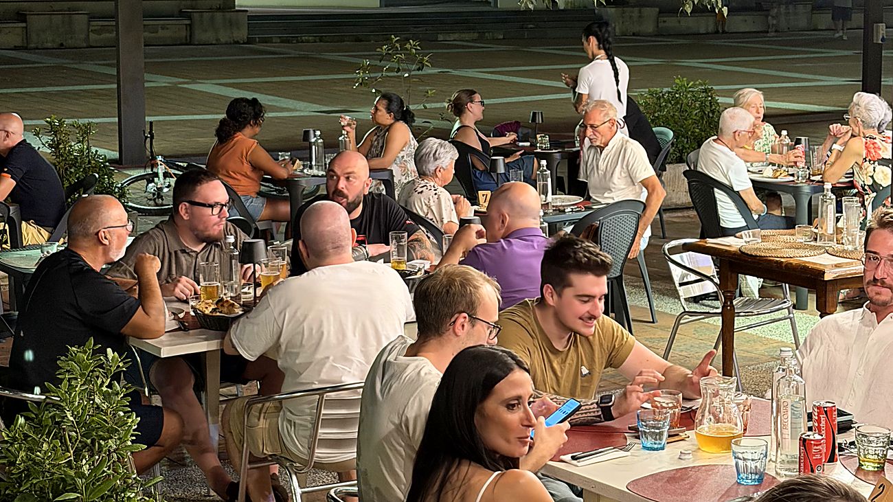 I tavoli all'aperto della pizzeria pieni, una sera d'estate