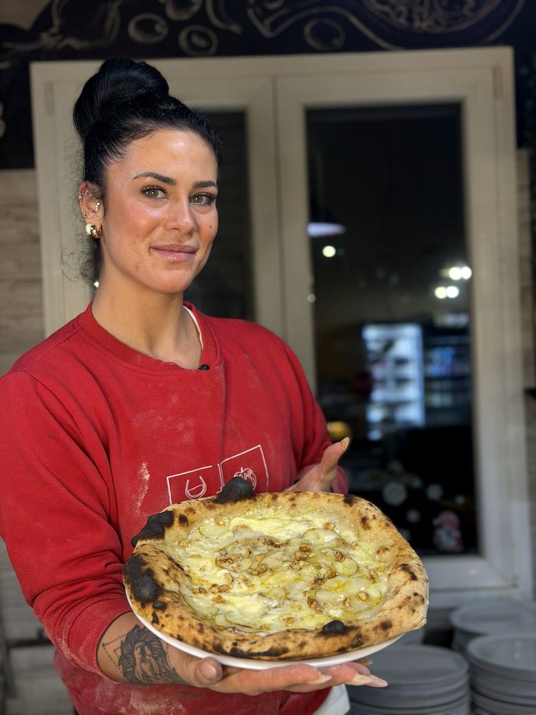 La pizzaiola dell'Angolo Rosso con una pizza appena sfornata